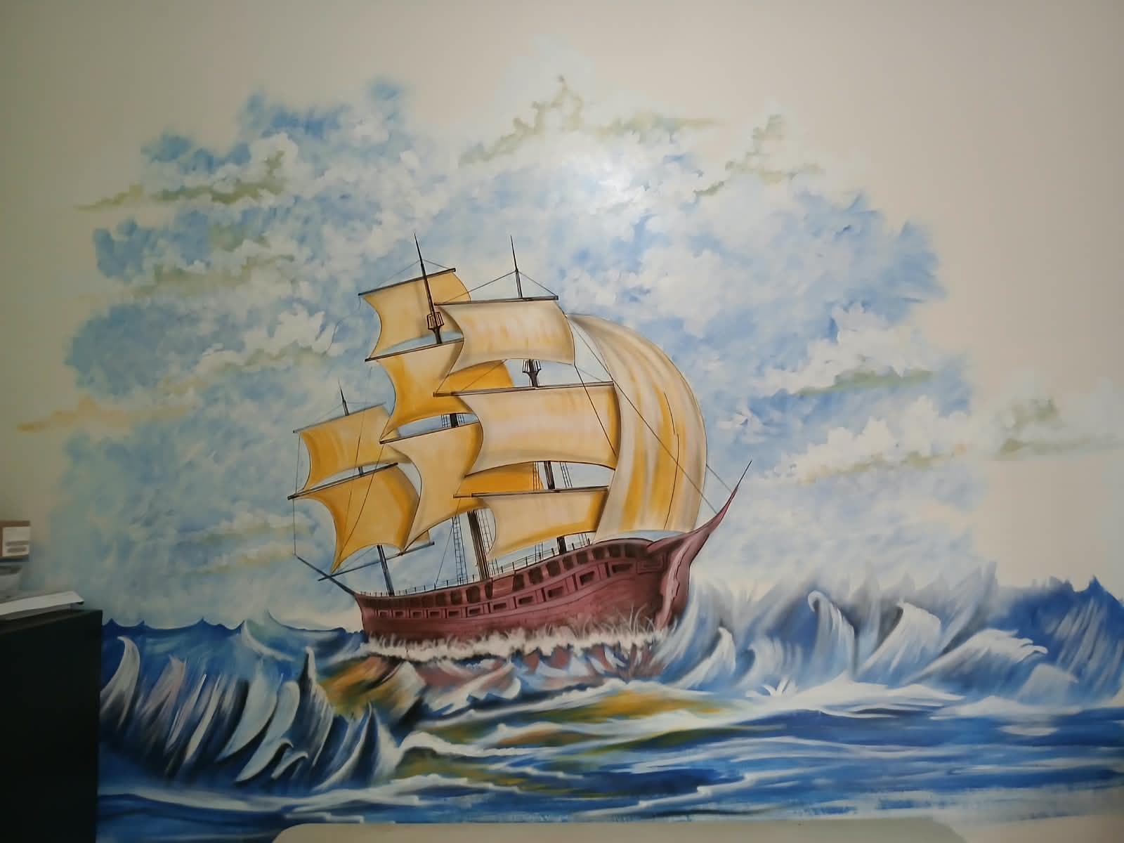 Mural de un barco de vela navegando entre grandes olas