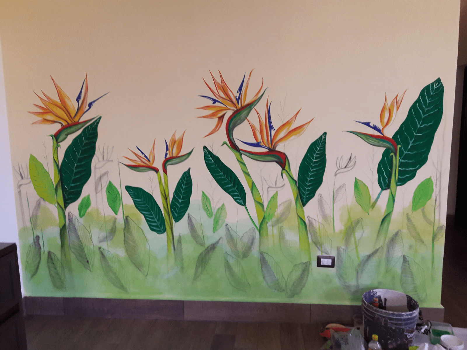 Mural de flores ave del paraíso y hojas tropicales pintadas en una pared