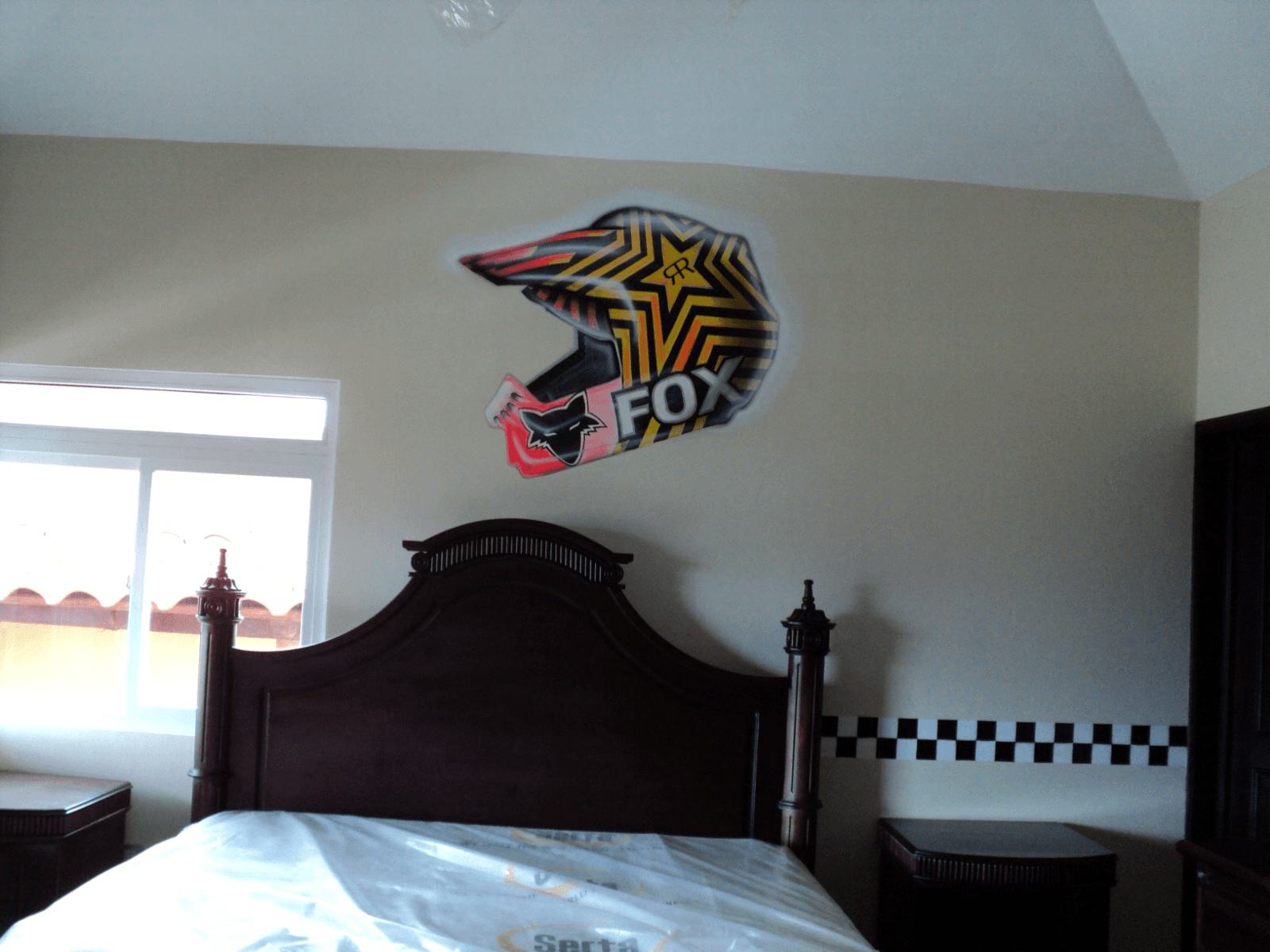Mural de un casco de motocross pintado sobre la cama de una habitación infantil