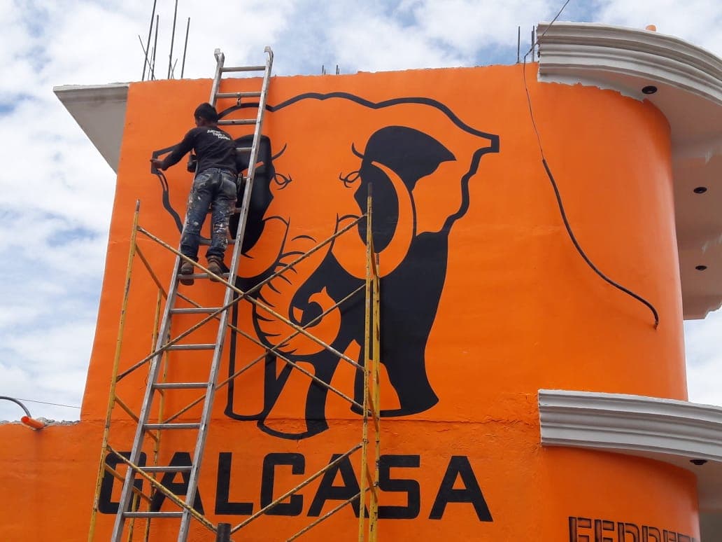 Rotulación de Galcasa pintada a mano sobre una fachada naranja